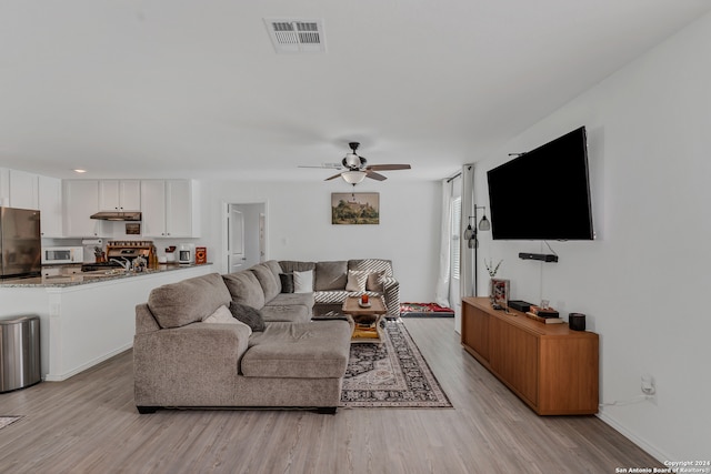 living room with light hardwood / wood-style flooring and ceiling fan