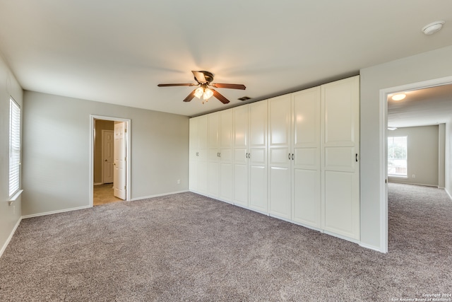 unfurnished bedroom featuring light carpet, a closet, and ceiling fan