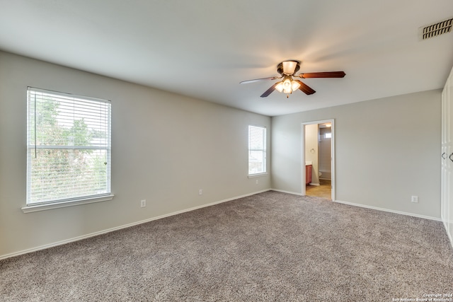 carpeted spare room with ceiling fan and plenty of natural light