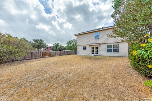 rear view of house with french doors and a lawn