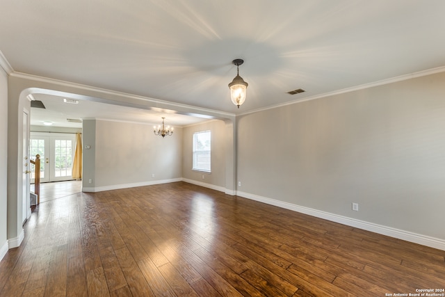 spare room with a notable chandelier, ornamental molding, plenty of natural light, and dark hardwood / wood-style flooring