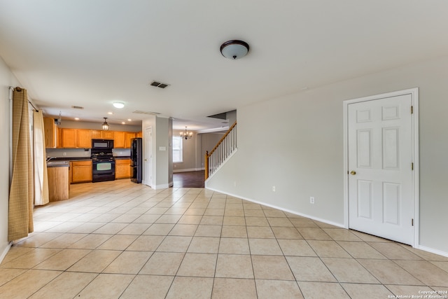 unfurnished living room with an inviting chandelier and light tile patterned floors