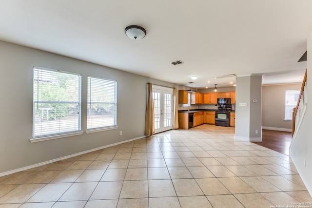 unfurnished living room with french doors, light tile patterned floors, and plenty of natural light