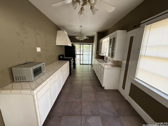 140 Jeffrey, San Antonio, TX 78201 - kitchen featuring black gas stove, tile countertops, a sink, and white cabinets