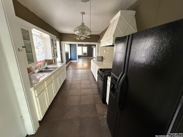 kitchen featuring black appliances, sink, dark hardwood / wood-style flooring, decorative light fixtures, and tile counters