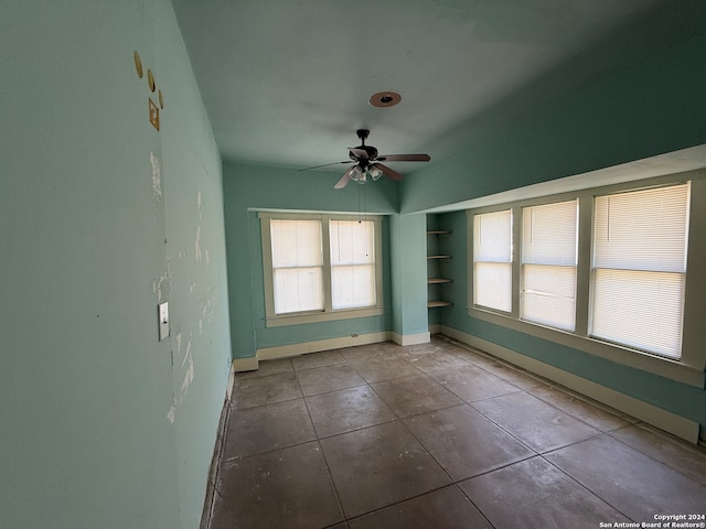 tiled empty room featuring a wealth of natural light and ceiling fan