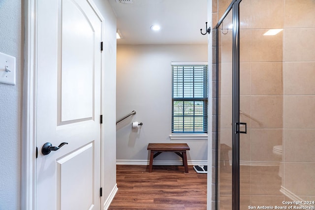 bathroom with toilet, an enclosed shower, and hardwood / wood-style flooring