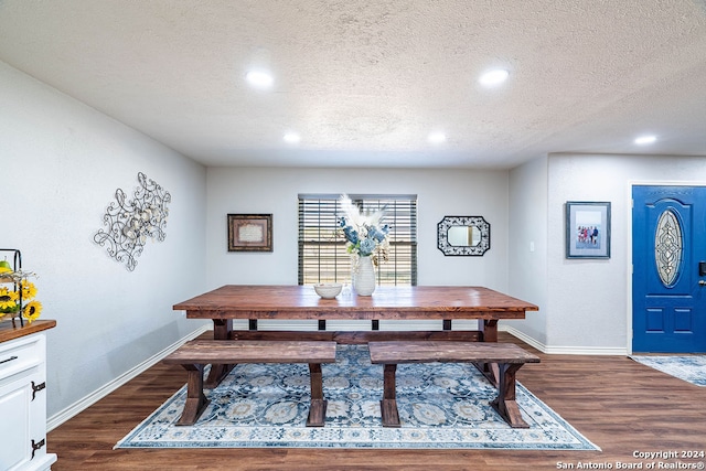 dining space with dark wood-type flooring and a textured ceiling