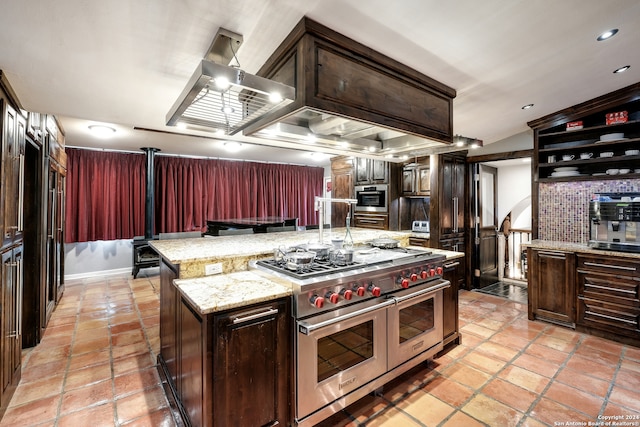 kitchen with light stone counters, stainless steel appliances, dark brown cabinets, and a kitchen island