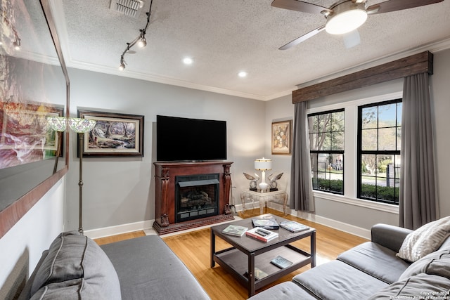 living room featuring crown molding, rail lighting, a textured ceiling, and light hardwood / wood-style floors