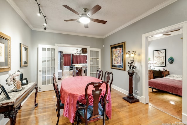 dining area with ceiling fan, a textured ceiling, light wood-type flooring, ornamental molding, and french doors