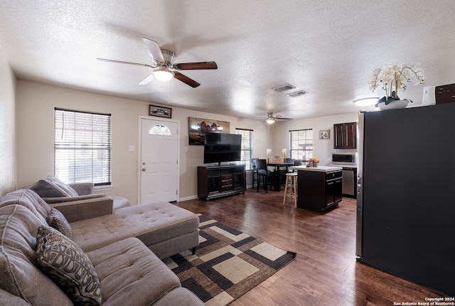 living room featuring a textured ceiling, dark hardwood / wood-style floors, and ceiling fan