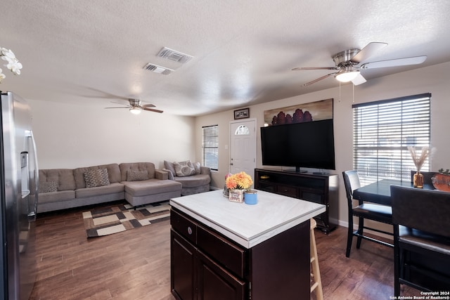 kitchen featuring a textured ceiling, dark hardwood / wood-style floors, a center island, and stainless steel fridge with ice dispenser