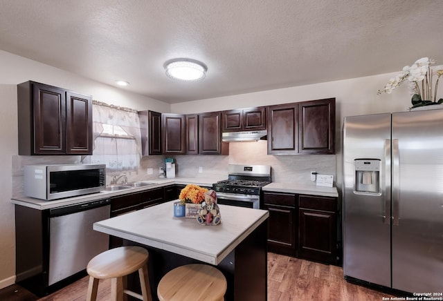 738 Kendalia Ave, San Antonio, TX 78221 - kitchen with dark brown cabinets, a sink, light countertops, under cabinet range hood, and stainless steel appliances