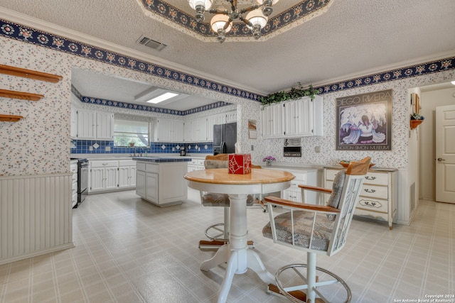 kitchen featuring a kitchen island, black refrigerator, range, white cabinetry, and a textured ceiling