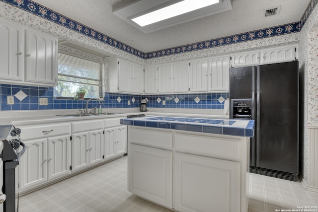 kitchen featuring sink, electric range oven, a textured ceiling, white cabinetry, and black fridge with ice dispenser