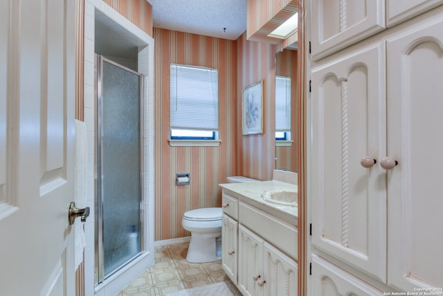 bathroom with a shower with door, vanity, a textured ceiling, and toilet