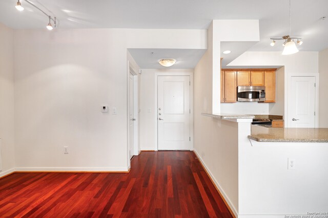 interior space featuring light stone countertops, kitchen peninsula, and dark hardwood / wood-style floors