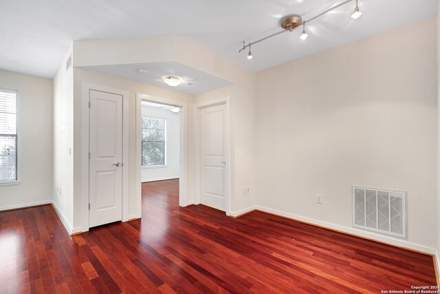 unfurnished room with rail lighting and dark hardwood / wood-style floors