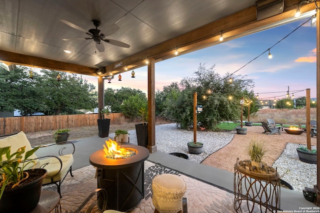 patio terrace at dusk featuring a fire pit and ceiling fan