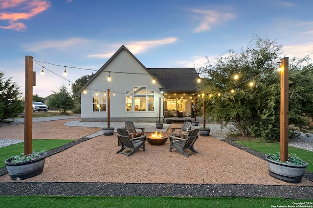 back house at dusk with an outdoor fire pit and a patio area