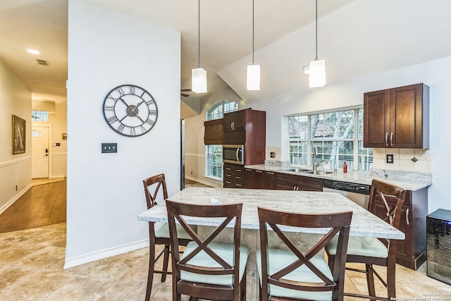 kitchen featuring lofted ceiling, decorative backsplash, stainless steel appliances, sink, and decorative light fixtures