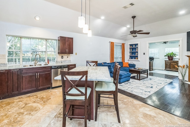 kitchen featuring sink, a kitchen breakfast bar, pendant lighting, stainless steel dishwasher, and light hardwood / wood-style flooring