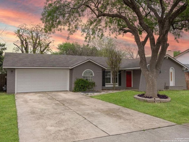 single story home featuring a lawn and a garage