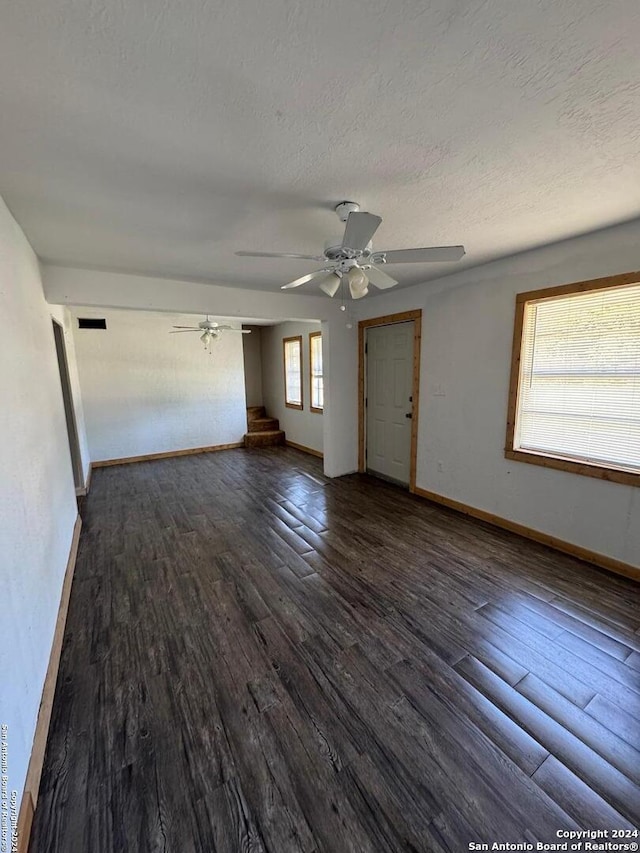 spare room featuring dark wood-type flooring, a textured ceiling, a healthy amount of sunlight, and ceiling fan