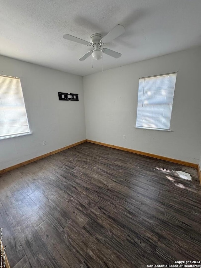 unfurnished room with a textured ceiling, dark wood-type flooring, and ceiling fan