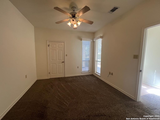 empty room with ceiling fan and dark colored carpet