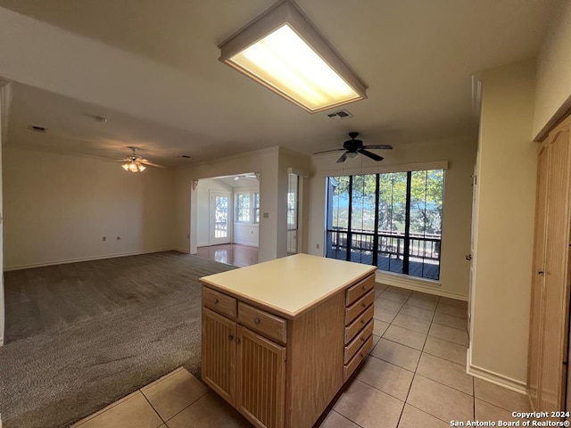 kitchen featuring light carpet, ceiling fan, a center island, and a wealth of natural light