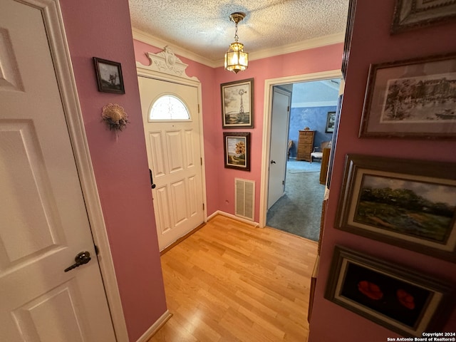 entryway featuring a textured ceiling, light hardwood / wood-style flooring, and ornamental molding