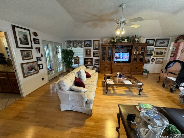 living room featuring hardwood / wood-style floors, ceiling fan, french doors, and vaulted ceiling