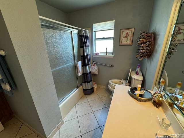 bathroom featuring tile patterned floors, combined bath / shower with glass door, and toilet