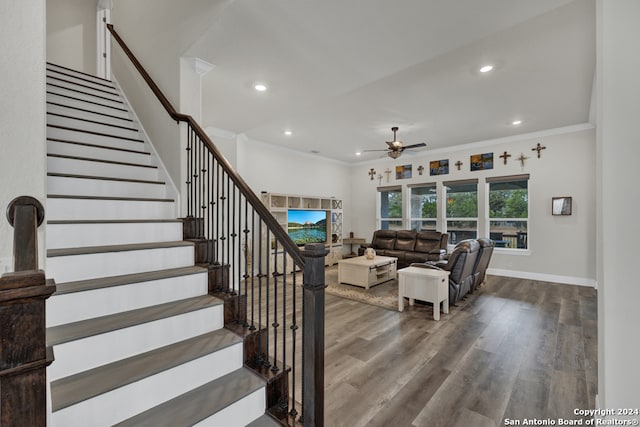 living room featuring ceiling fan, crown molding, baseboards, and wood finished floors