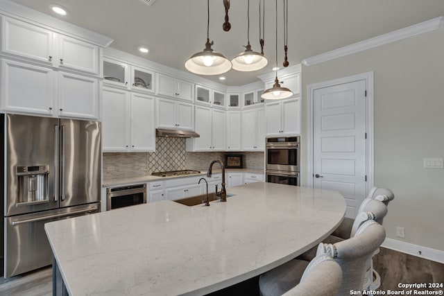 kitchen featuring a breakfast bar area, a sink, ornamental molding, appliances with stainless steel finishes, and tasteful backsplash