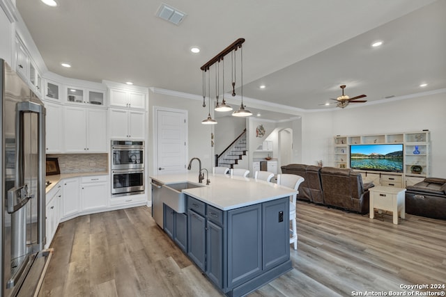 kitchen featuring arched walkways, blue cabinetry, stainless steel appliances, open floor plan, and a sink