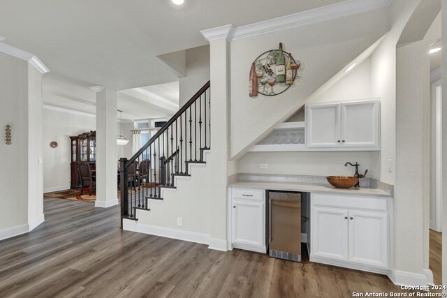 1207 Game Trl, New Braunfels, TX 78132 - indoor wet bar featuring stairway, dark wood-style flooring, refrigerator, ornamental molding, and baseboards