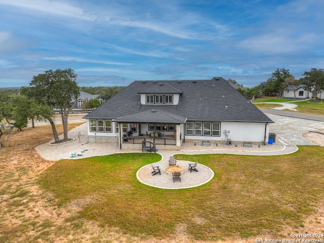 rear view of property with a patio, an outdoor fire pit, a lawn, and a sunroom