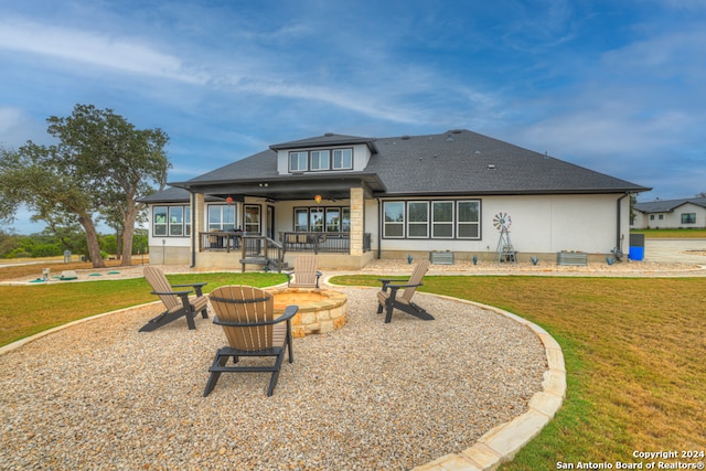 back of house with a shingled roof, a fire pit, a lawn, and a patio