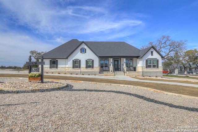 french country inspired facade with a shingled roof