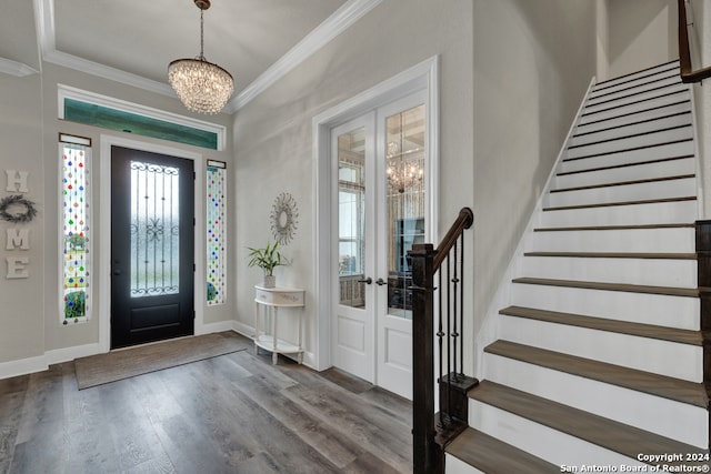 entryway featuring an inviting chandelier, baseboards, ornamental molding, and wood finished floors