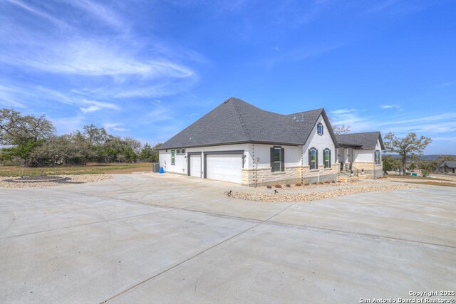 1207 Game Trl, New Braunfels, TX 78132 - view of side of home featuring concrete driveway, an attached garage, stucco siding, and a shingled roof