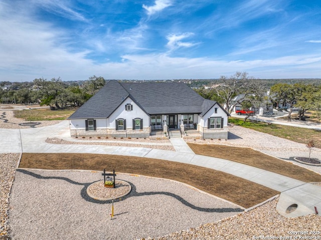 view of front of property with a shingled roof, curved driveway, and stucco siding