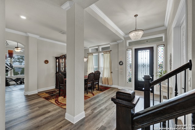 entryway featuring stairs, arched walkways, wood finished floors, and ornamental molding