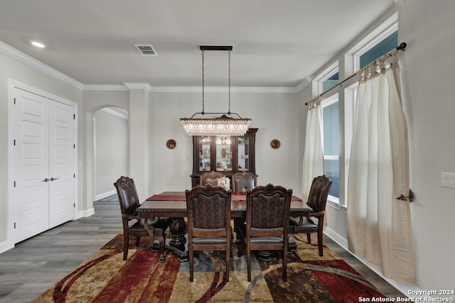 dining area featuring arched walkways, wood finished floors, visible vents, and crown molding