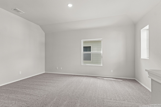 carpeted spare room featuring vaulted ceiling