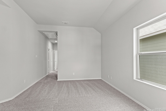 unfurnished room with a healthy amount of sunlight, light colored carpet, and vaulted ceiling