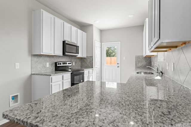 kitchen featuring sink, white cabinetry, stainless steel appliances, light stone counters, and decorative backsplash